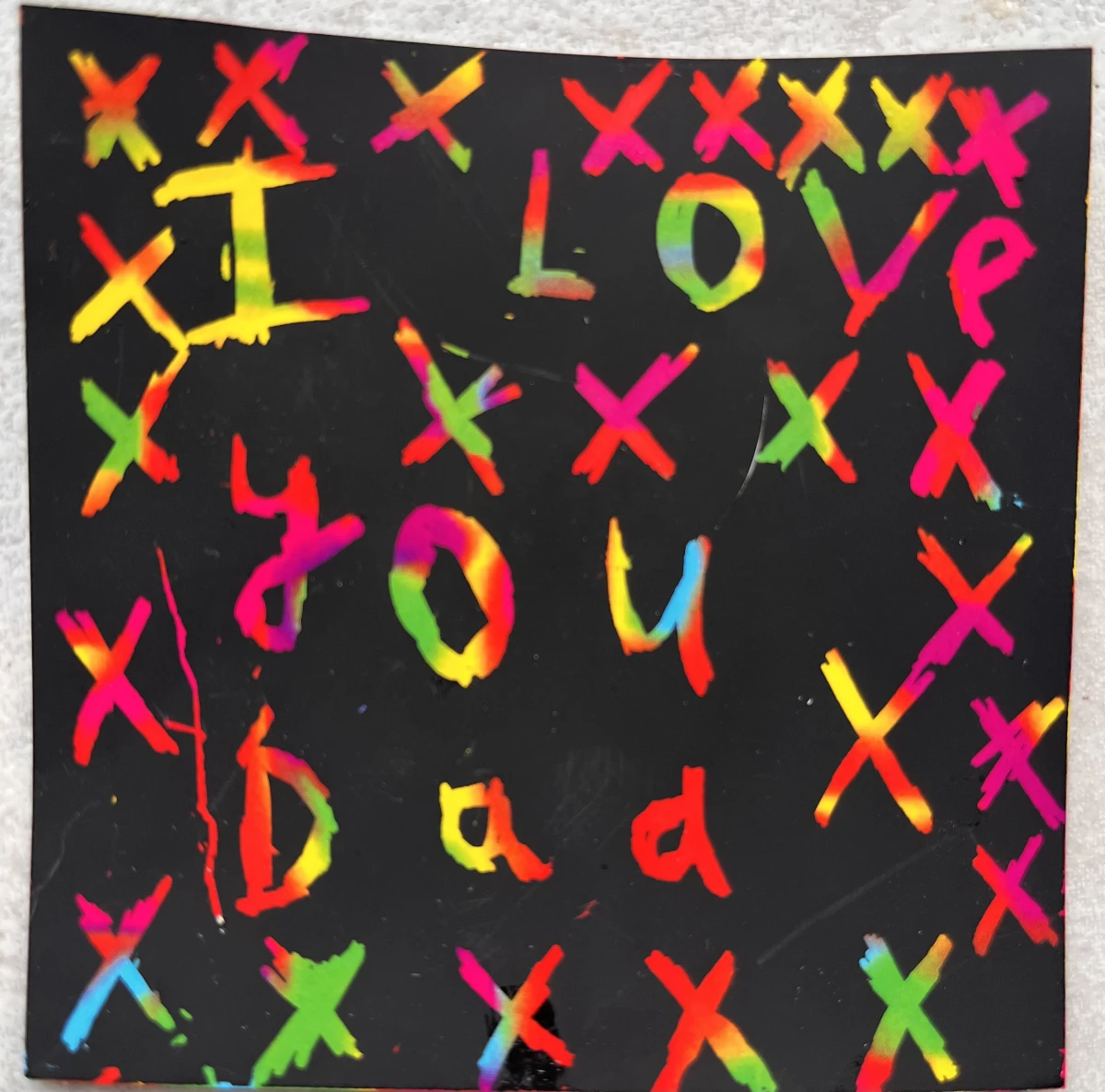 A multi-coloured message from my son with lots of kisses, that reads "I love you Dad"